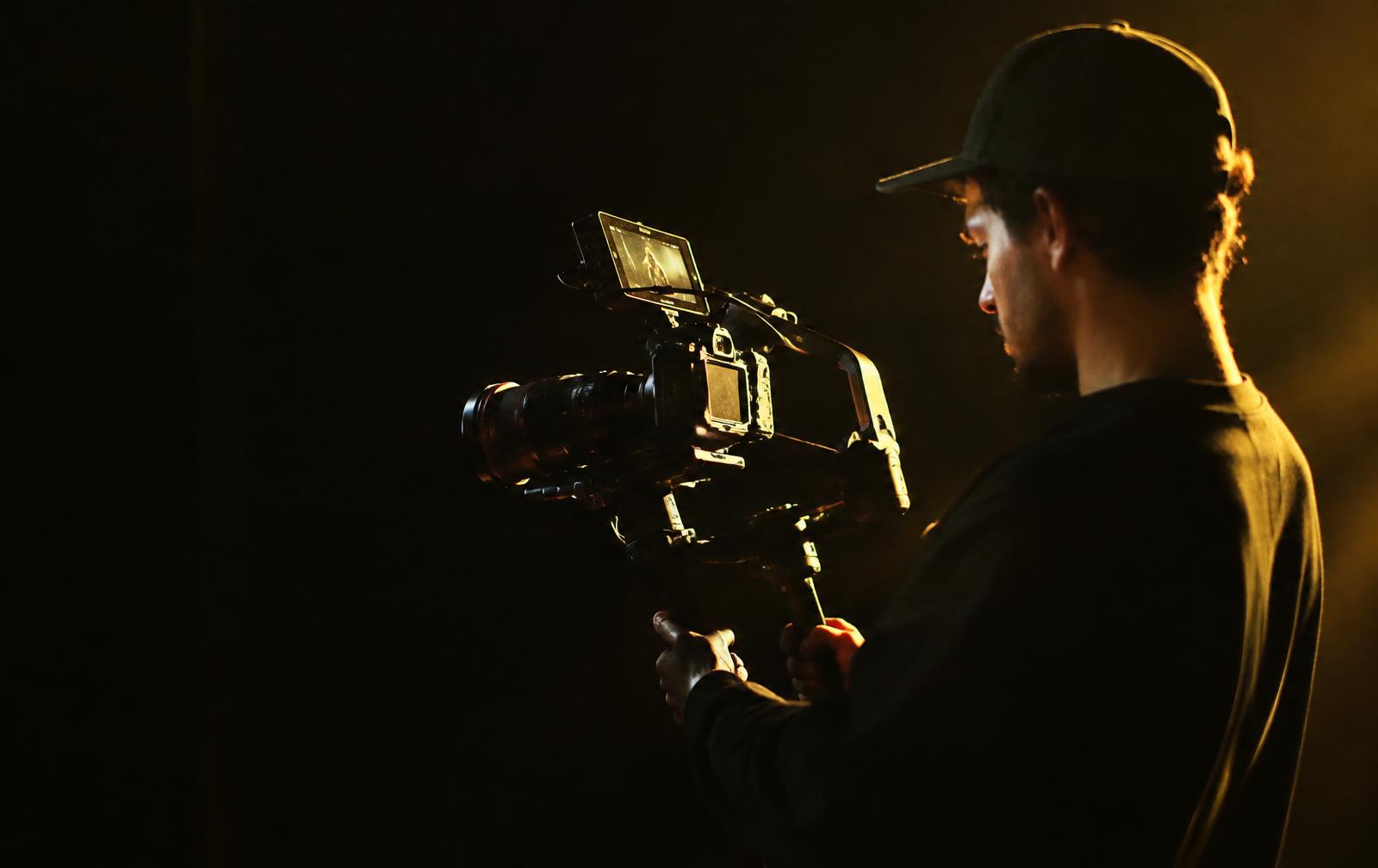 HIVE videographer filming with a cinema camera under golden studio light